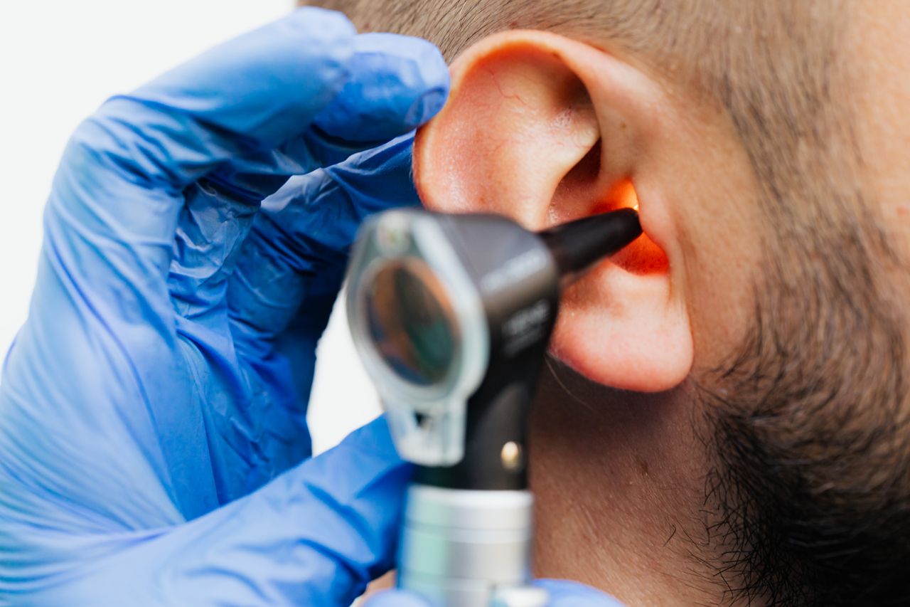 Close-up of a doctor using an otoscope to examine a patients ear in a clinical setting.