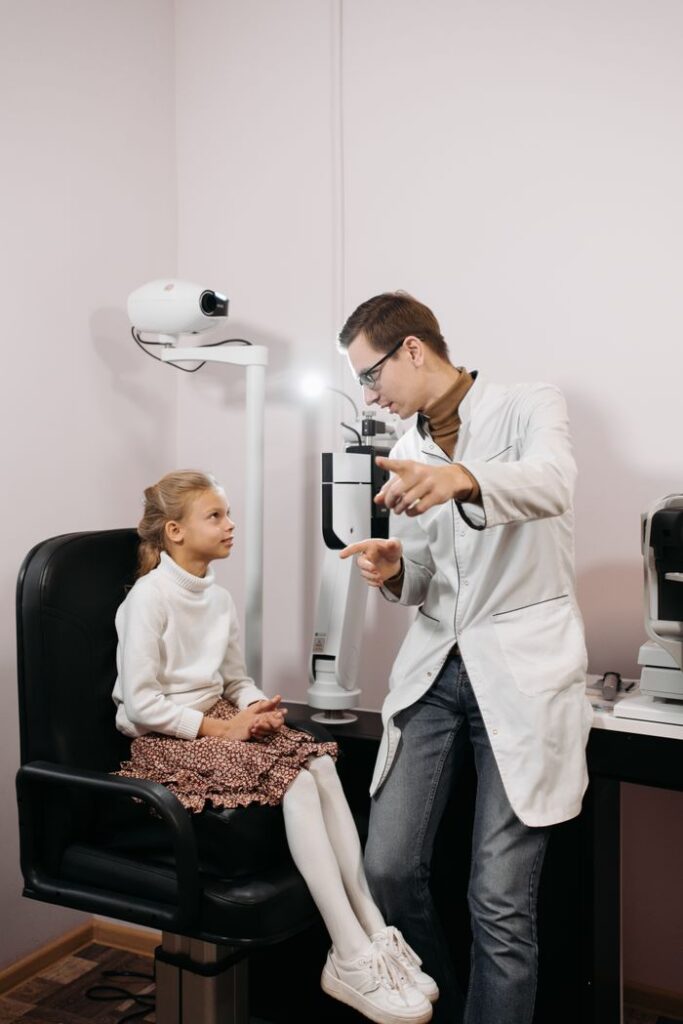 Eye doctor examining a young girl in a clinic setting with ophthalmological equipment.